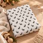 Black Reindeer Crib Sheet folded on a wooden table