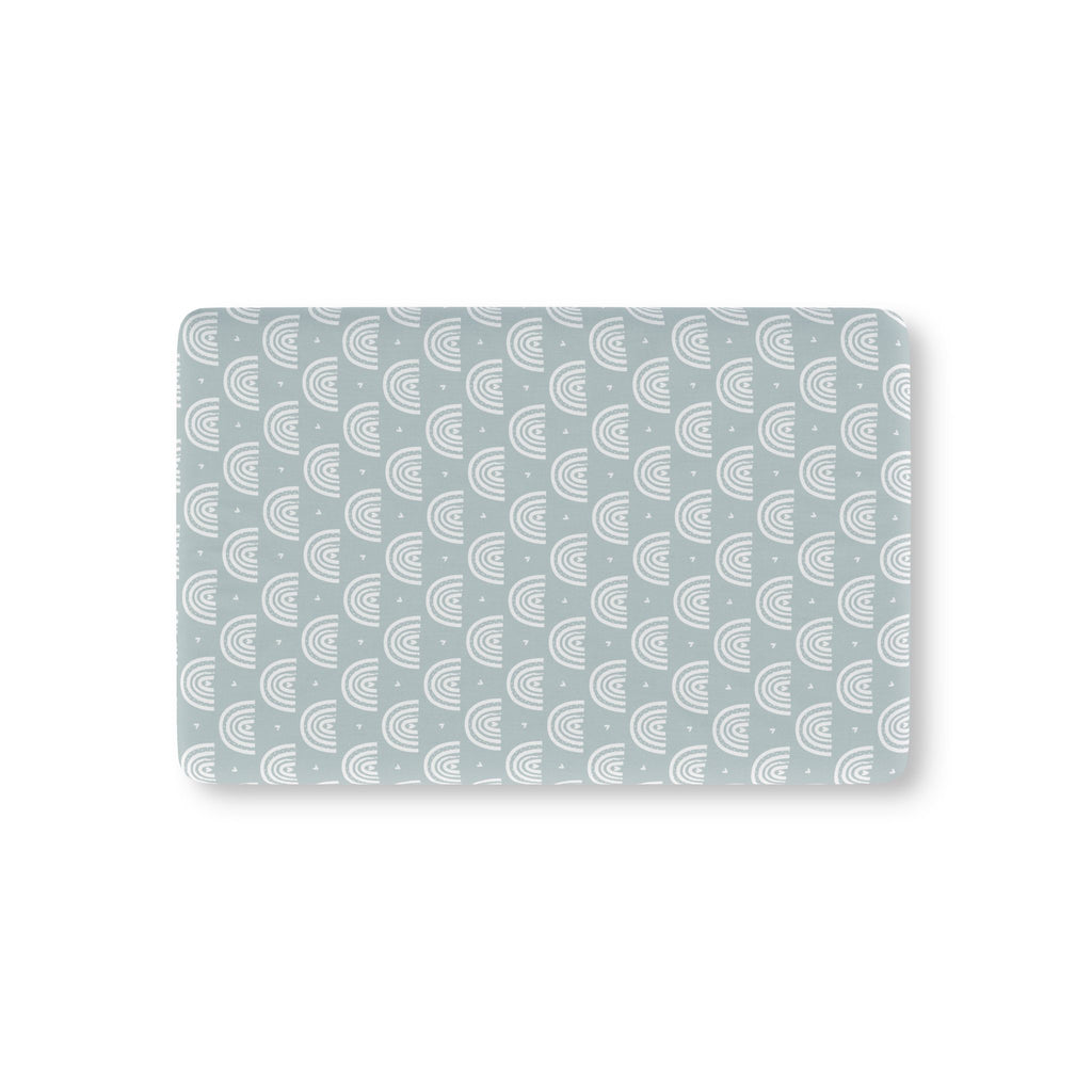 Blue Boho Rainbow Crib Sheet laid flat in Mini size with white rainbow arches on dusty blue