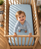 Toddler standing in a crib fitted with the Blue Heart Stripe Crib Sheet