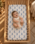 Smiling baby lying on the Blue Snowman Crib Sheet