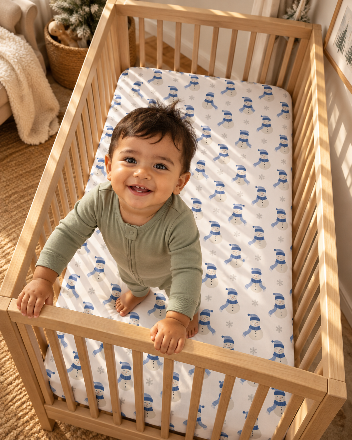 Toddler standing in a crib fitted with the Blue Snowman Crib Sheet