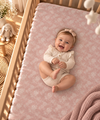 Smiling baby lying on the Blush Pink Lace Floral Crib Sheet