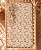 Cream Pumpkin Ghost Crib Sheet seen from above in a wooden crib