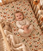 Smiling baby lying on the Fall Dachshund Crib Sheet