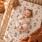 Smiling baby lying on the Fall Woodland Animal Crib Sheet