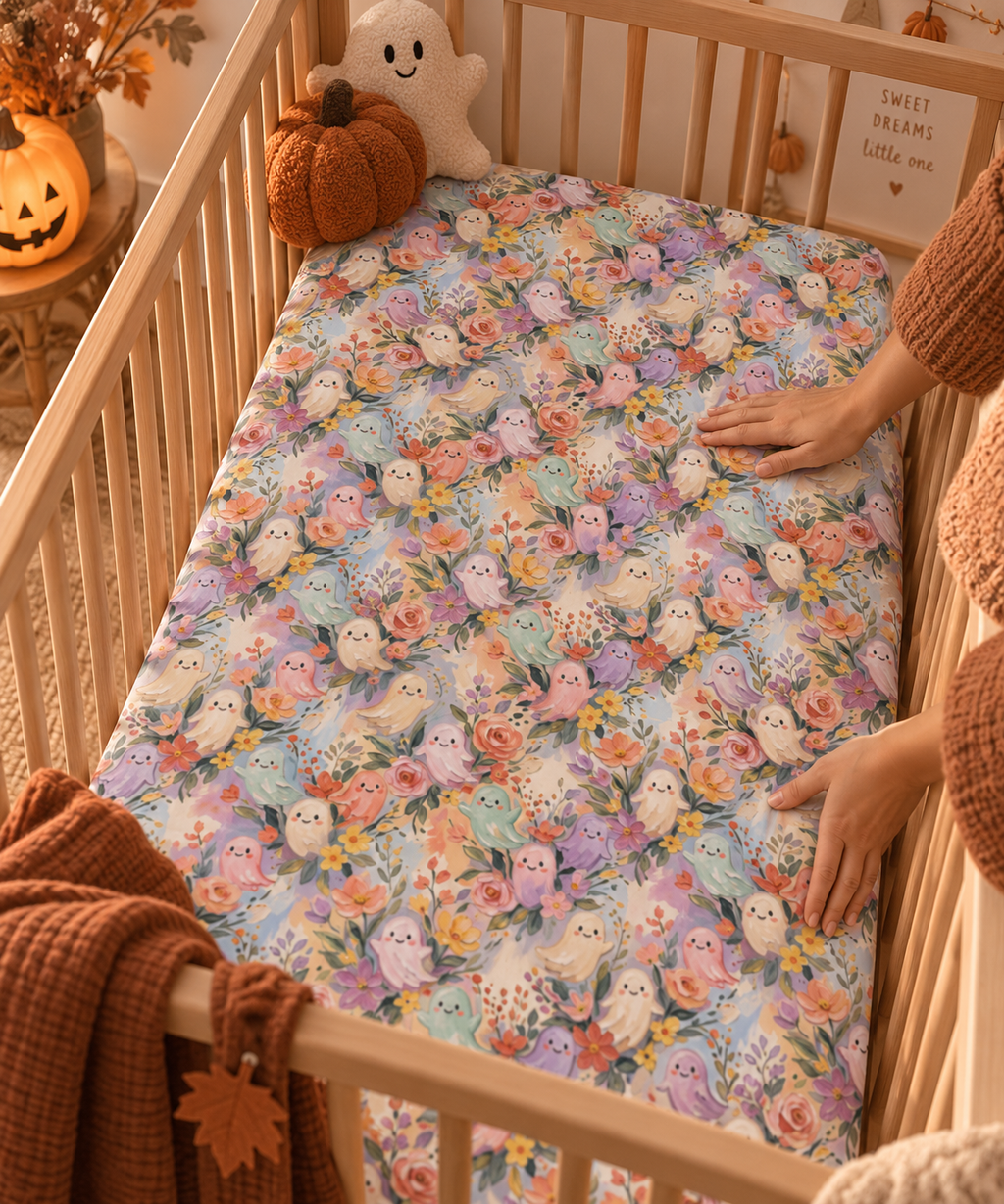 Hands smoothing the Floral Ghost Crib Sheet over a crib mattress