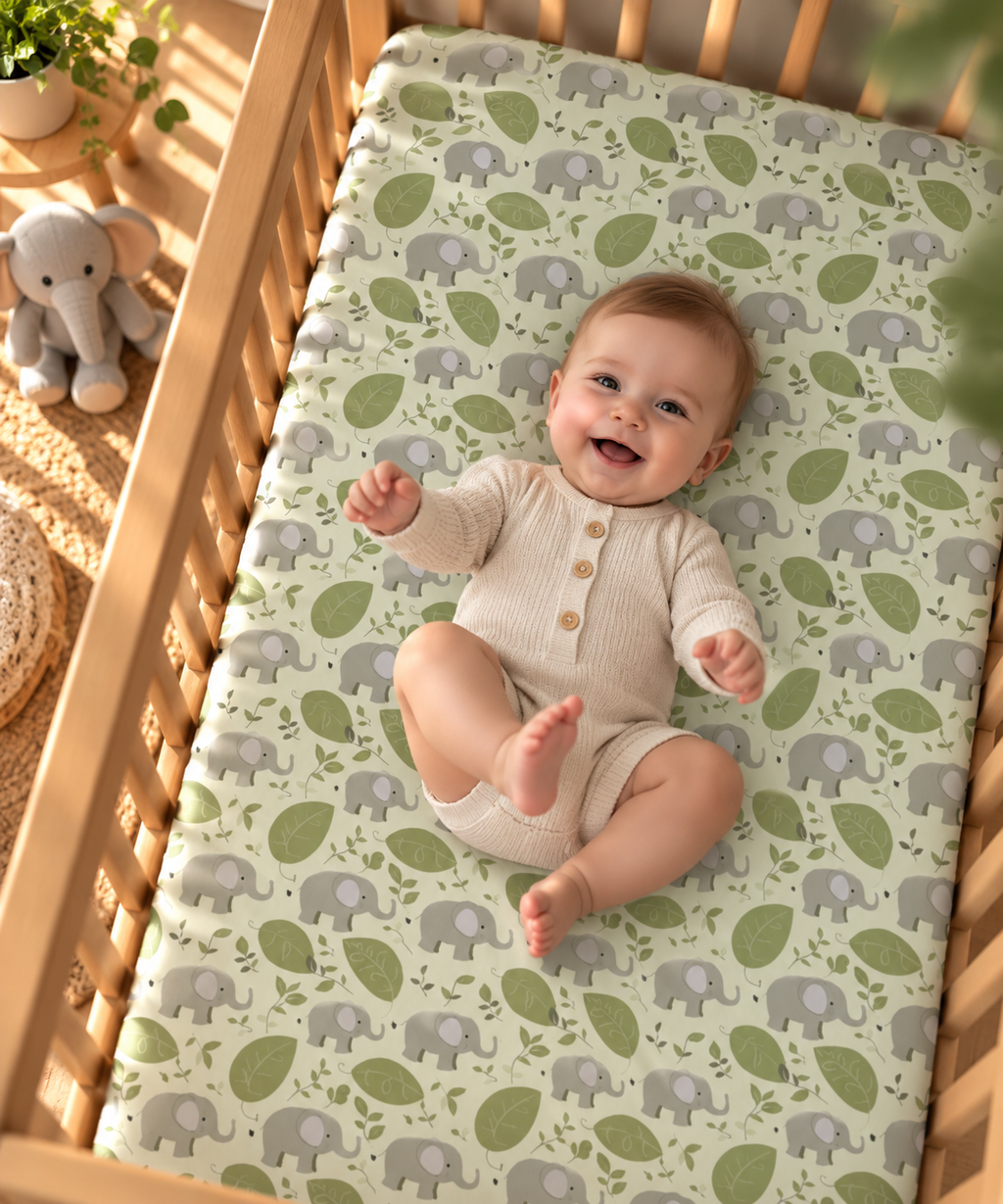 Smiling baby lying on the Green Elephant Crib Sheet