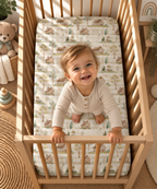 Toddler standing in a crib fitted with the Green Gingham Cottage Crib Sheet