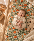 Smiling baby lying on the Green Gingham Pumpkin Crib Sheet