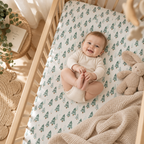 Smiling baby lying on the Green Pine Tree Crib Sheet