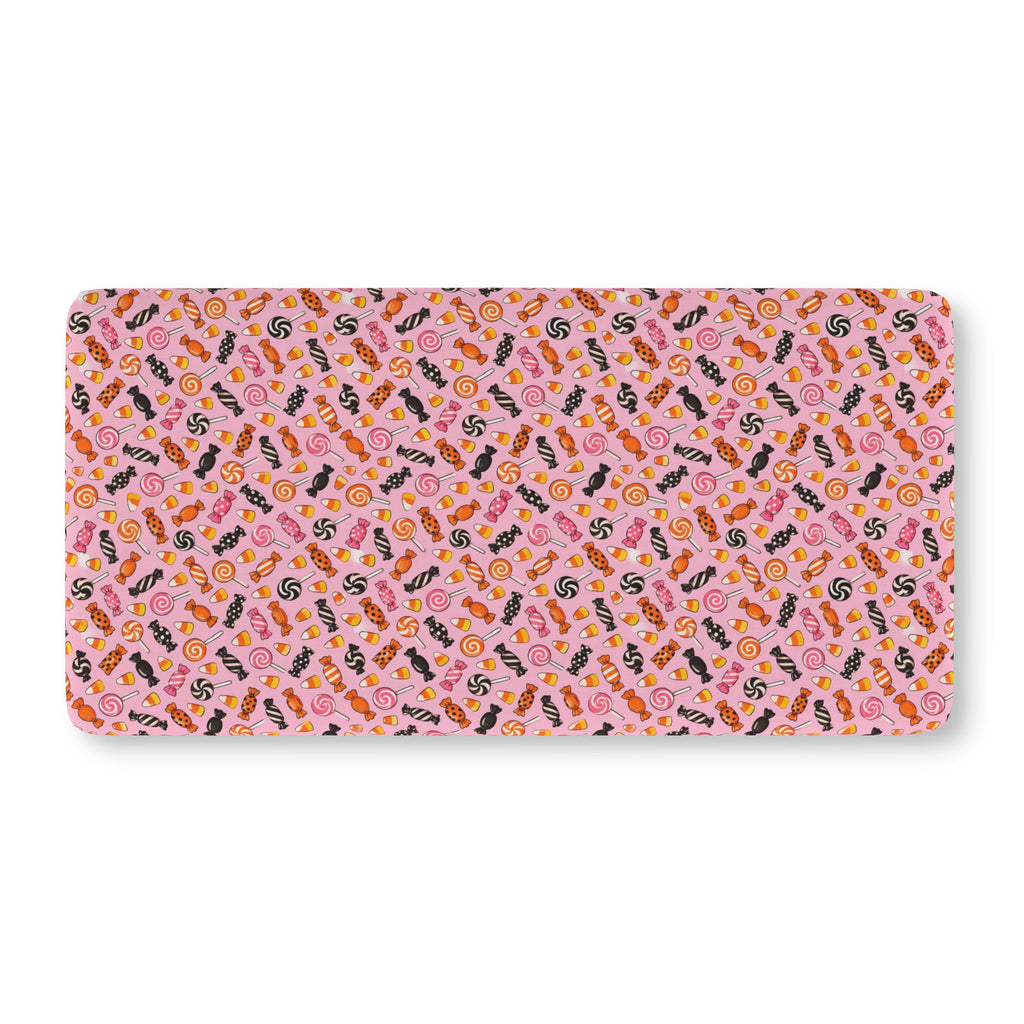 Halloween Candy Crib Sheet laid flat in Standard size with wrapped candy, lollipops and candy corn on pink