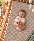 Smiling baby lying on the Mauve Boho Rainbow Crib Sheet