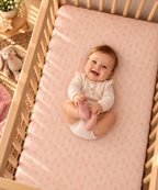 Smiling baby lying on the Peach Polka Dot Crib Sheet