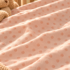 Close-up of the Peach Polka Dot Crib Sheet fabric showing watercolor dots on peach pink
