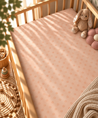 Peach Polka Dot Crib Sheet fitted in a wooden crib with a plush toy