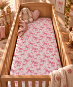 Pink Bow Crib Sheet on a wooden crib mattress in a baby girl nursery