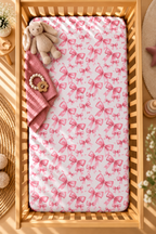 Pink Bow Crib Sheet seen from above in a wooden crib