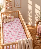 Pink Bow Crib Sheet in a wooden crib in a sunlit nursery