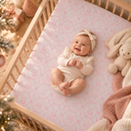 Smiling baby lying on the Pink Christmas Toile Crib Sheet