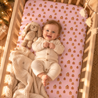 Smiling baby lying on the Pink Gingerbread House Crib Sheet