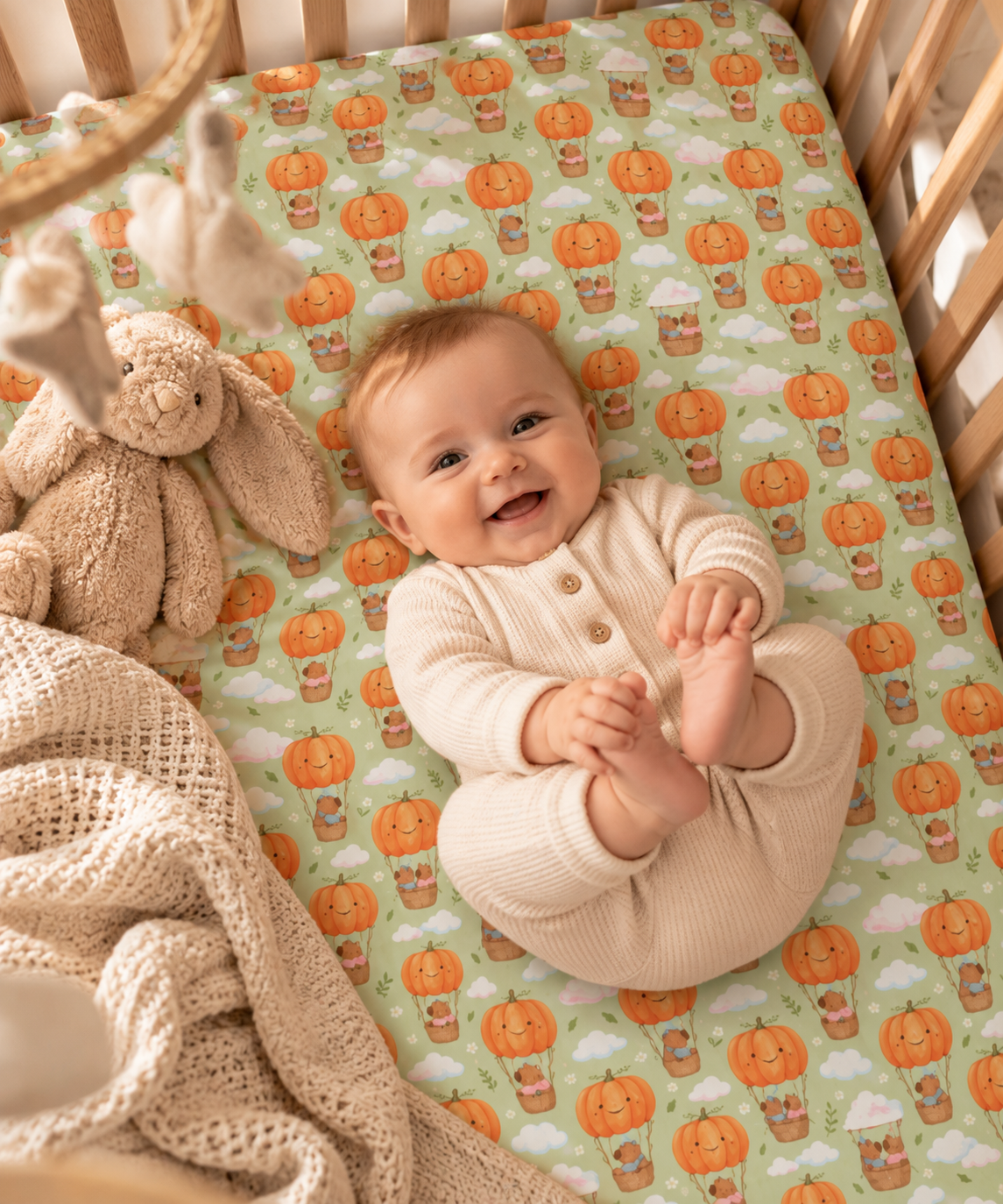 Smiling baby lying on the Pumpkin Bear Crib Sheet