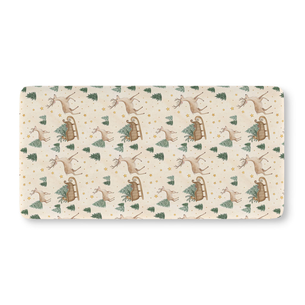 Reindeer Sleigh Crib Sheet laid flat in Standard size with reindeer, sleighs and pine trees on cream