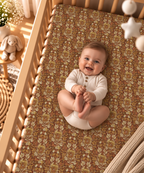 Smiling baby lying on the Rust Boho Floral Crib Sheet