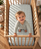 Toddler standing in a crib fitted with the Sage Gingham Heart Crib Sheet
