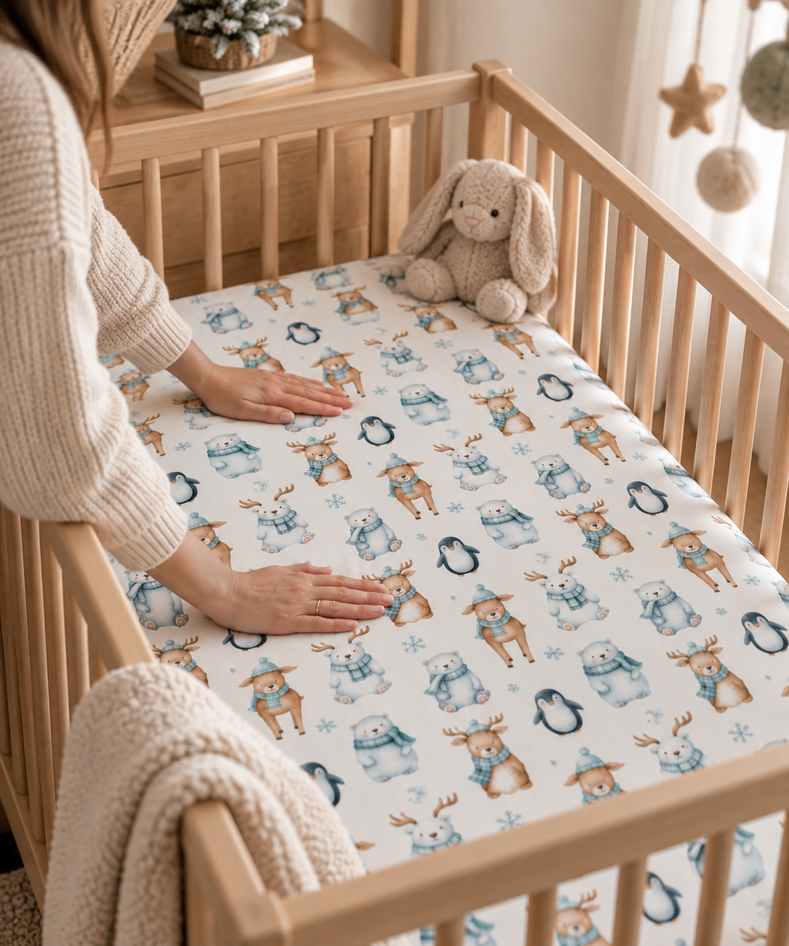 Hands smoothing the Winter Polar Bear Crib Sheet over a crib mattress